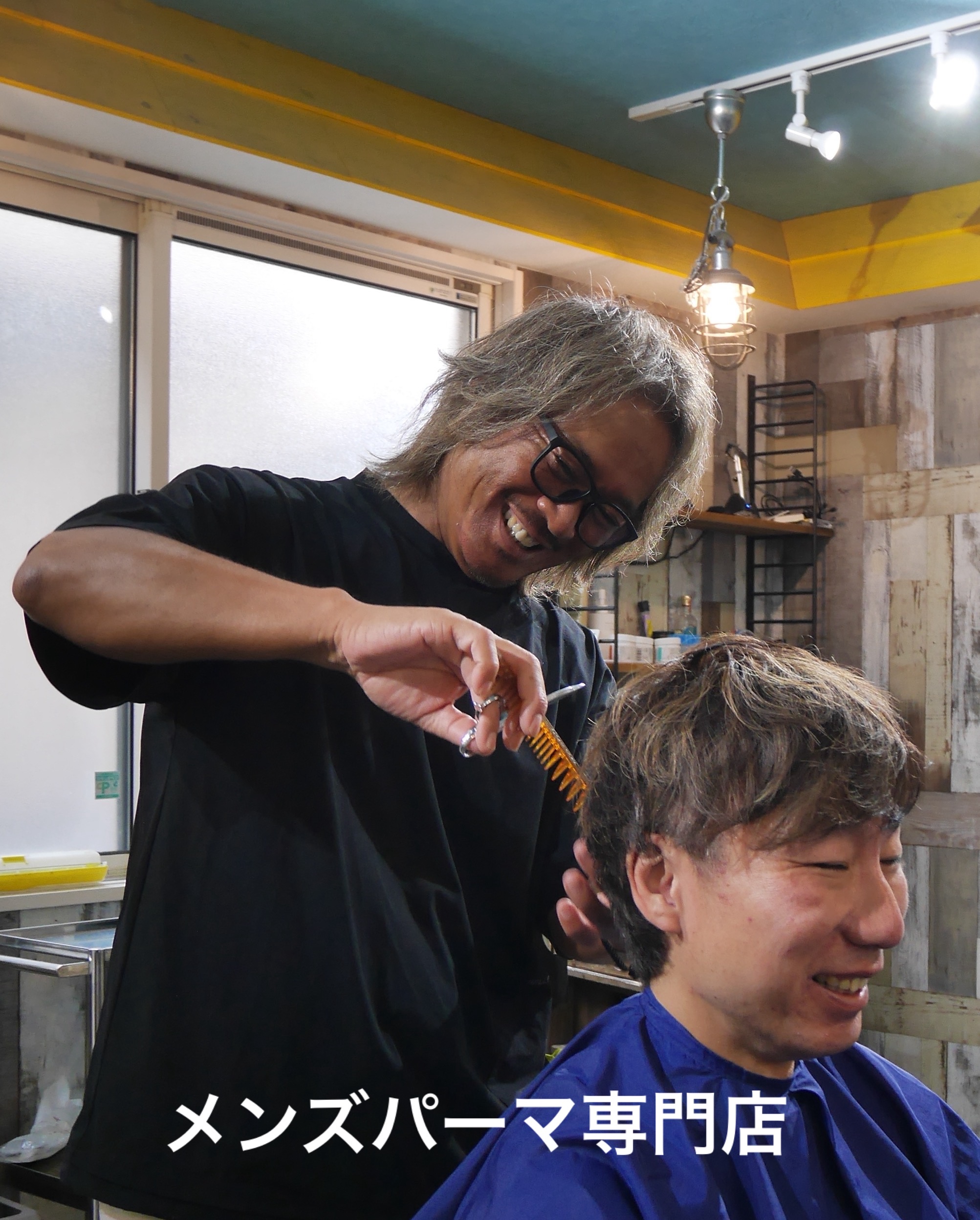 笑顔でメンズカットを施術するオーナー・兼重康浩